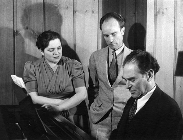 man at piano, man and woman watching